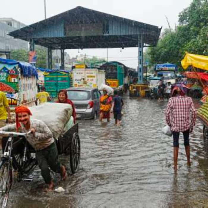 A cart-puller pulls his cart on a waterlogged road and vehicles stuck in traffic following rainfall, at Jahangirpuri, in New Delhi