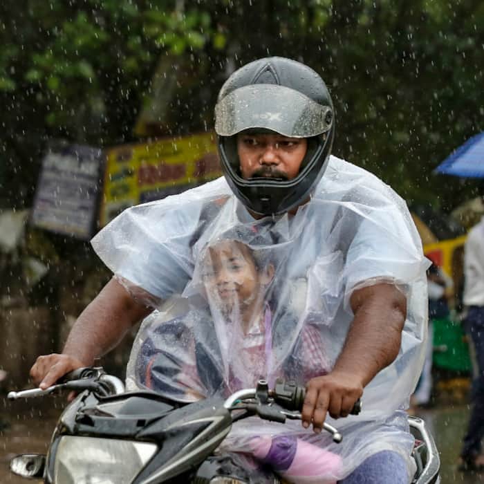 A commuter with a child makes his way amid heavy monsoon rain, in New Delhi, Tuesday.