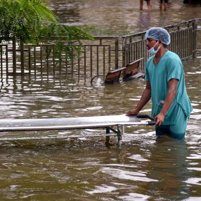 A hospital staff member carries a stretcher through a waterlogged area after heavy rain, at BHU Hospital, in Varanasi, Uttar Pradesh