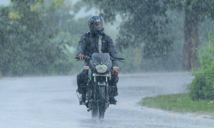 A man rides a motorcycle through heavy rain in the Nagaon district, Assam, on Tuesday