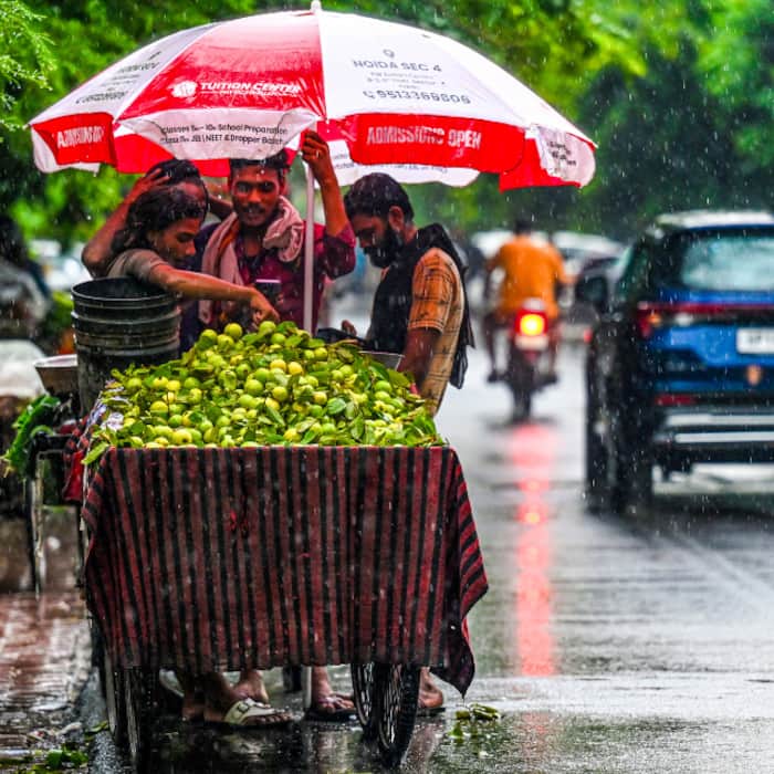 A roadside vendor sells guavas from his cart amid rainfall, in Noida