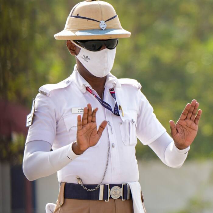 A traffic police officer covers his face to protect himself from the scorching heat while on duty, in Chennai