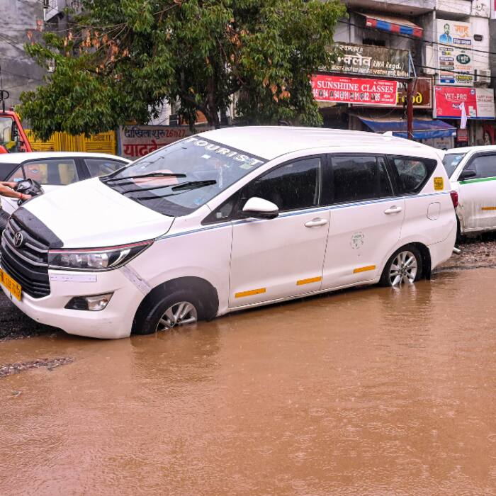 A vehicle stuck in a caved-in section of a road after heavy rainfall in the Burari area, New Delhi