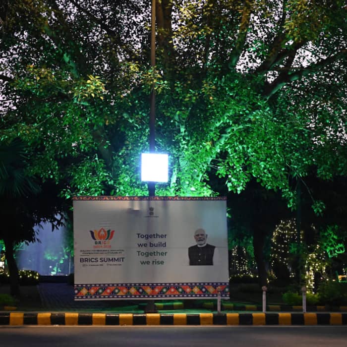 An illuminated BRICS India 2026 summit display featuring Prime Minister Narendra Modi and the theme Together we build, Together we rise .