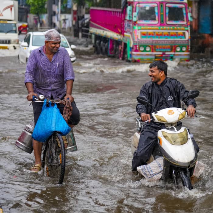 Commuters navigate a waterlogged road after heavy rainfall inundates several parts of the city, in Mumbai