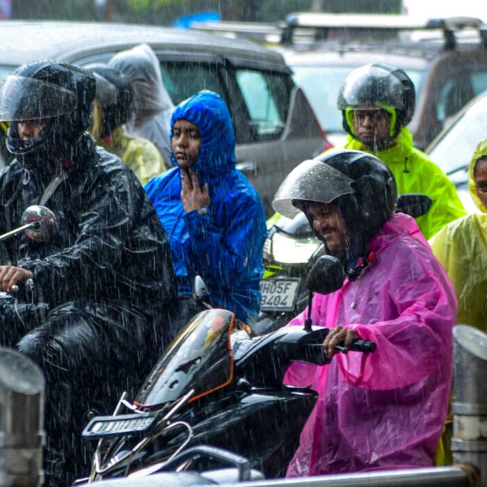 Commutters cover themselves amid rainfall, in Mumbai, Maharashtra, Monday
