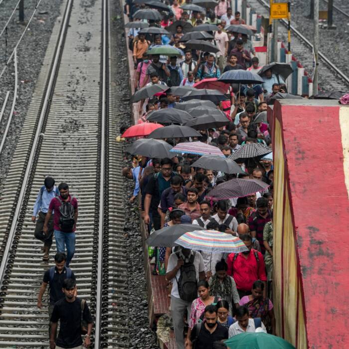 Daily commuters crowd a railway platform amid rainfall, in Kolkata on Friday