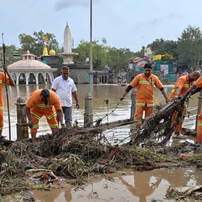 Municipal Corporation personnel carry out debris clearance near the Godavari riverbanks following heavy rain, in Nashik