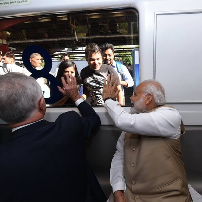 Narendra Modi and Australian PM Malcolm Turnbull waving to passengers at metro station