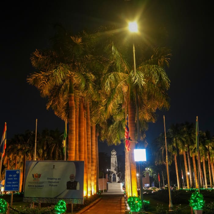 Palm trees and flags are illuminated as part of preparations ahead of the BRICS Summit, in the Teen Murti area of New Delhi.