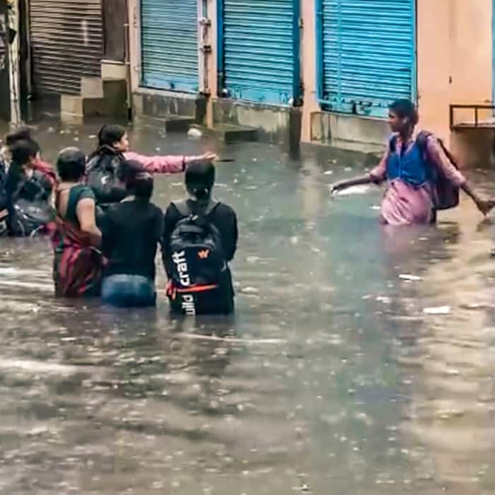 People move on a waterlogged area following rainfall, at Sangam Vihar, in New Delhi