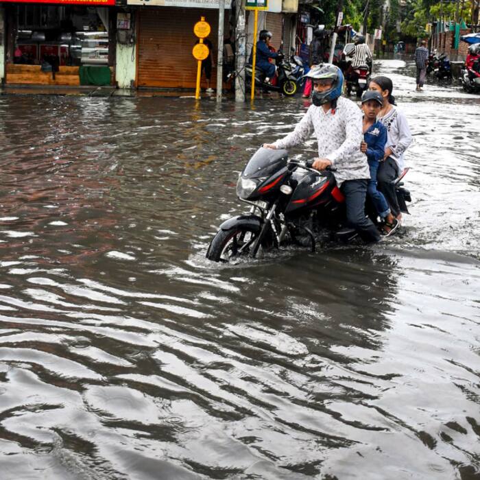 People on a two-wheeler make their way through a waterlogged road after heavy rainfall, in Guwahati
