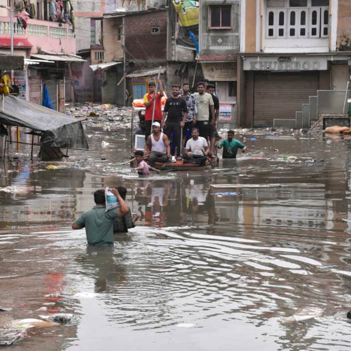 People use a boat to cross a waterlogged area following heavy rain, in Surat