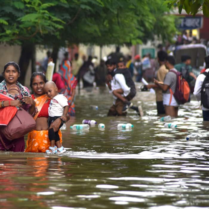 People wade through a waterlogged area after heavy rainfall, at BHU road, in Varanasi, Uttar Pradesh