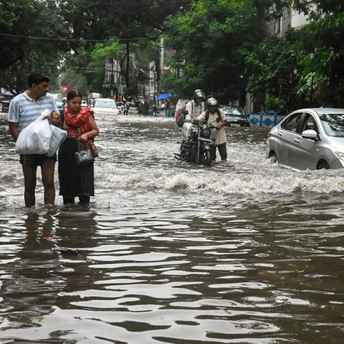 People wade through a waterlogged road after rainfall, in Kolkata, West Bengal