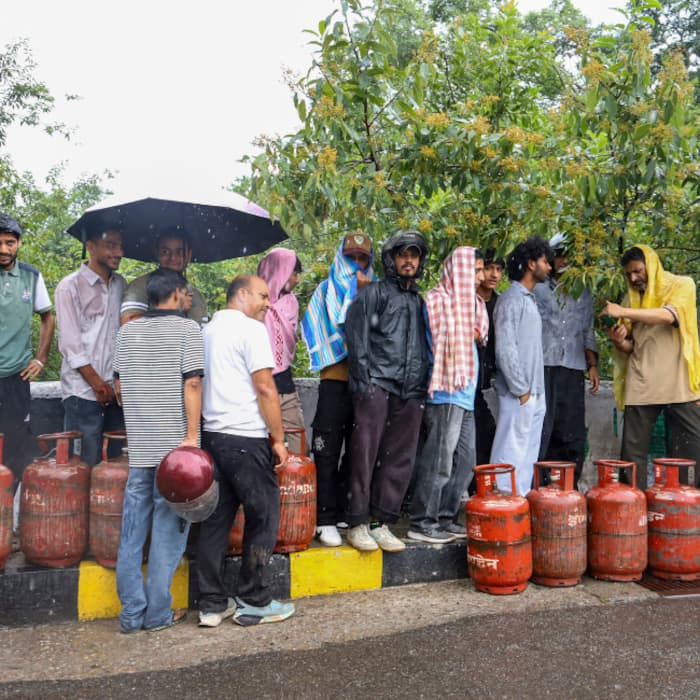 People wait in a queue to avail refilled LPG cylinders, in Dharamshala