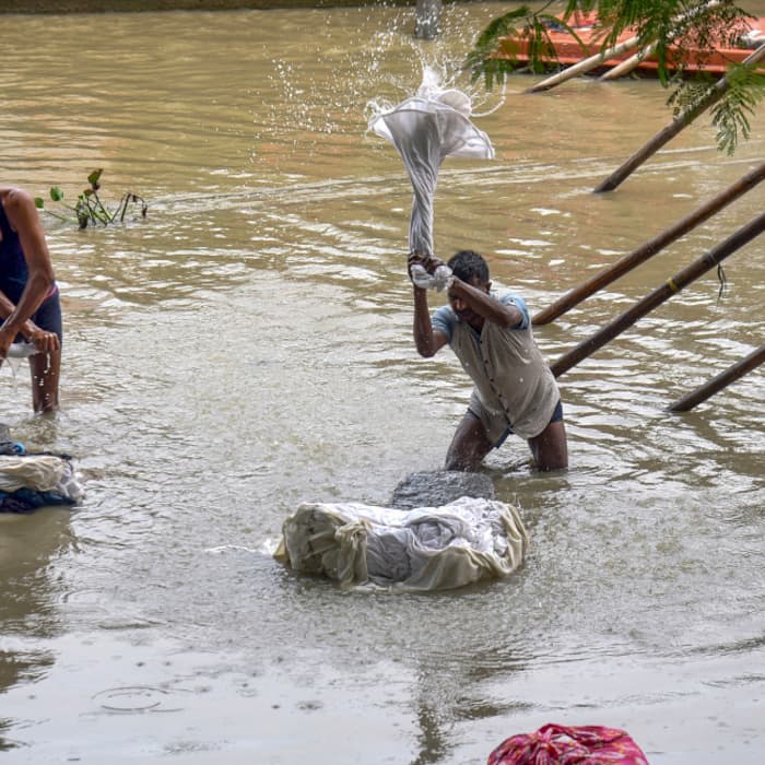 People wash their clothes as the water level of Brahmaputra river rises following heavy rainfall, in Guwahati, Assam
