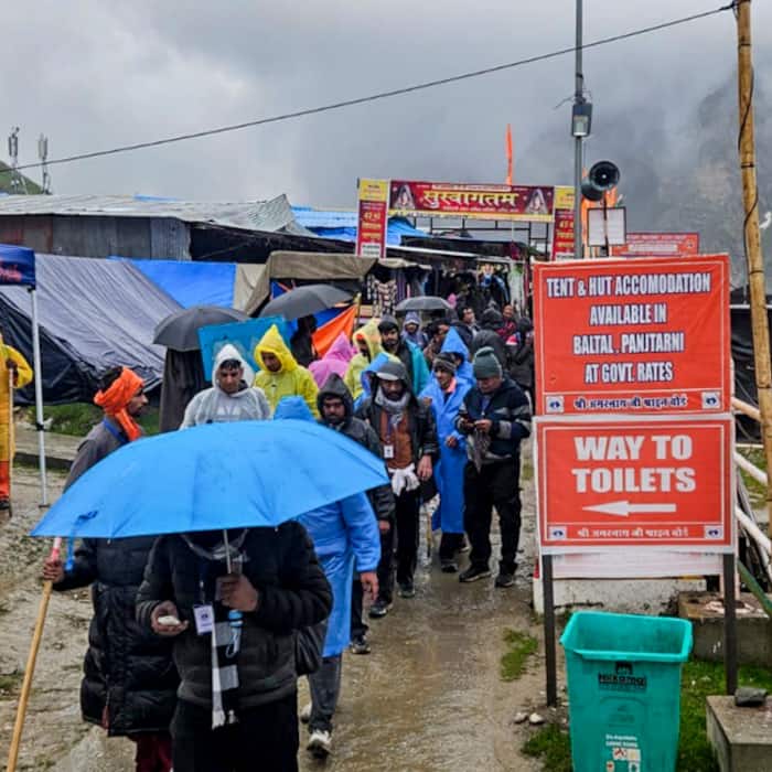 Pilgrims seek shelter from rain en route to the Amarnath cave shrine, at the Panjtarni transit camp in Pahalgam, Anantnag district.