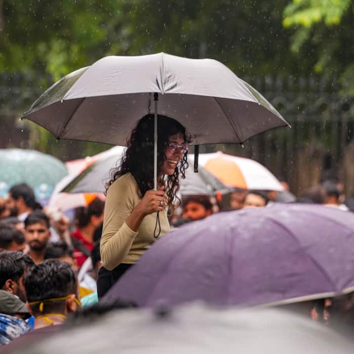 Protesters take shelter from rain during protest in Delhi