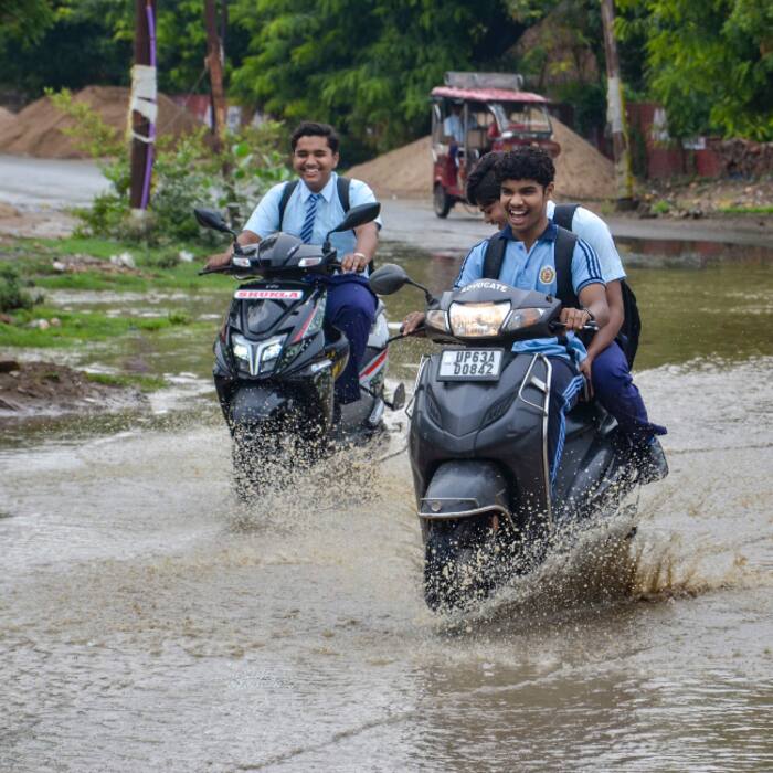 Students move on a waterlogged road amid rainy weather , in Mirzapur, Uttar Pradesh