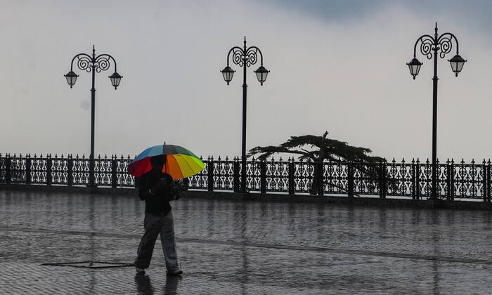 Visitors walk with umbrellas amid rain in Shimla