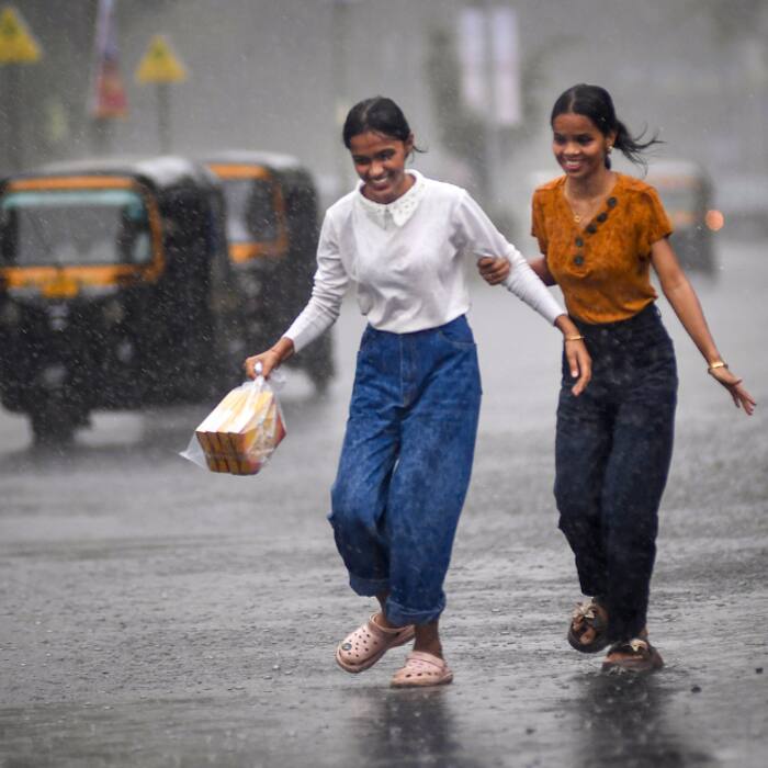 Women seek shelter amid rain, in Mumbai, Sunday