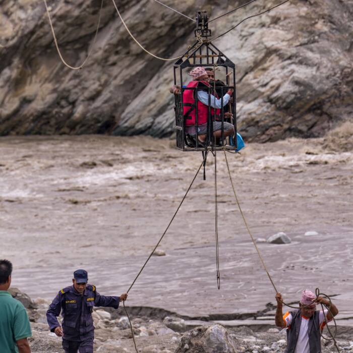 Workers pull ropes as people use a makeshift zipline to cross the Trishuli river from Koloni in the aftermath of the recent flash floods, in Nuwakot district.